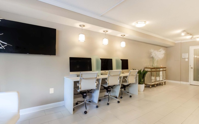 a room with white chairs computers and a television