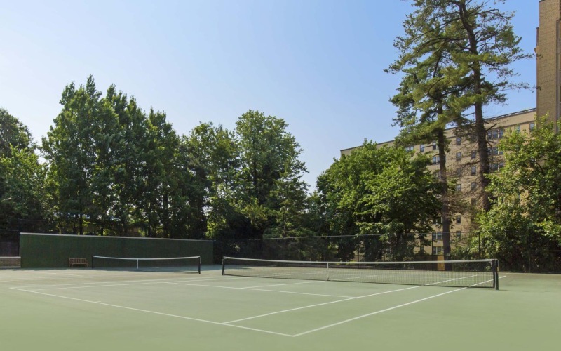 a tennis court with trees and buildings in the background